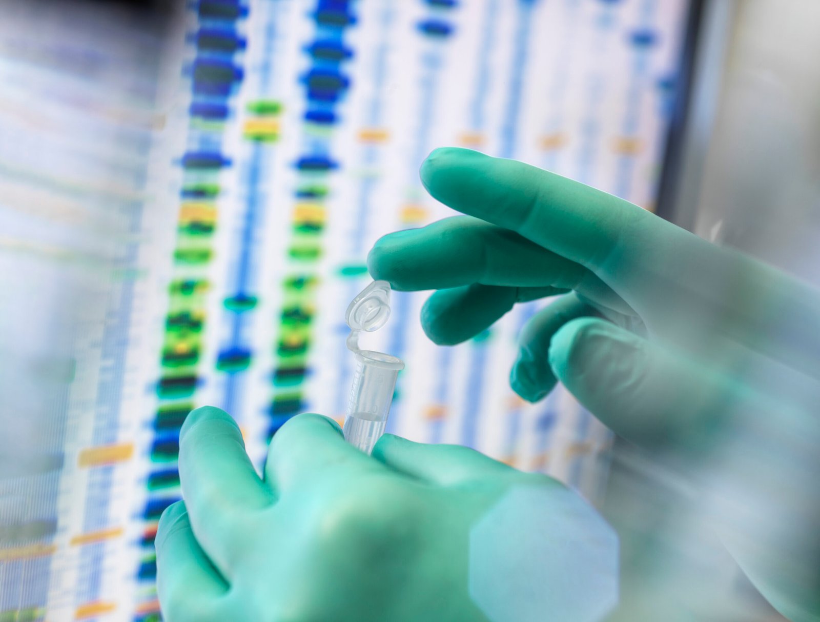 Scientist examining a sample in a lab with DNA sequencing gel in the background.